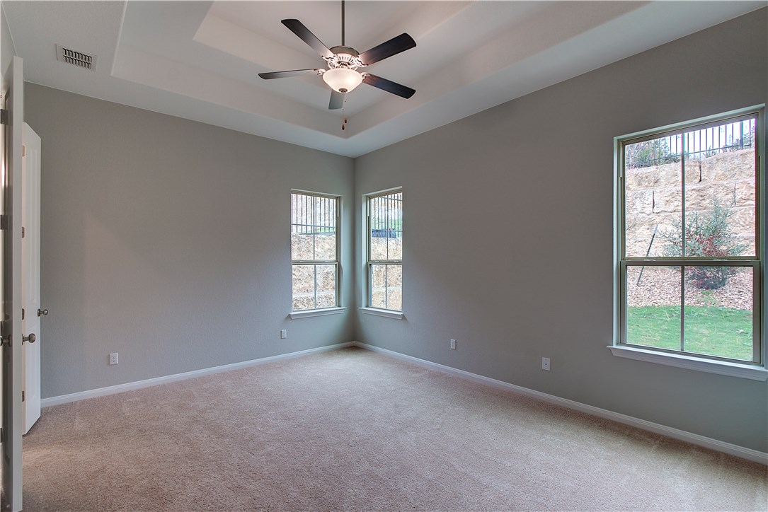 107 Cartwheel Bend Austin, TX 78738 - Photo 14 of 16 Empty room featuring ceiling fan, light colored carpet, and a tray ceiling