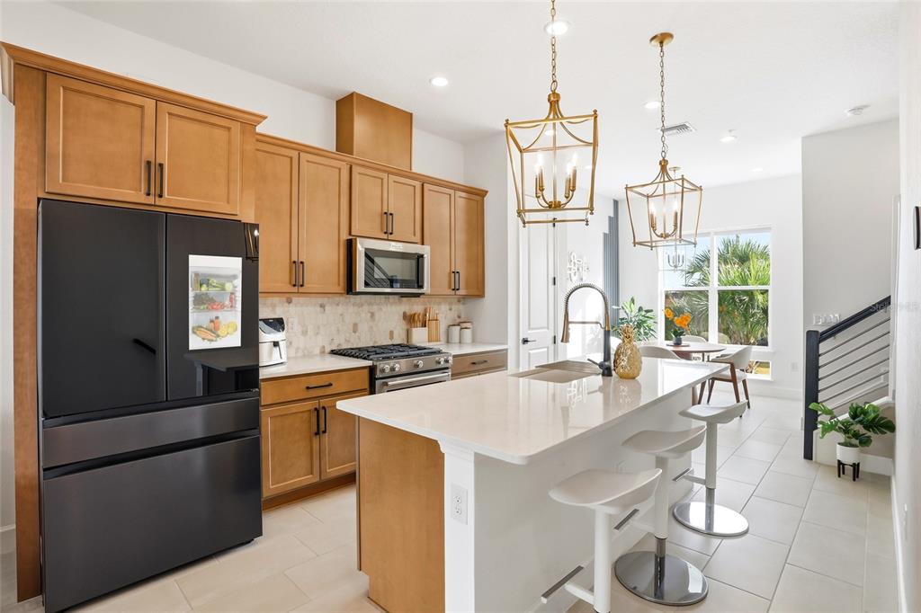 2038 Packing District Way Orlando, FL 32804 - Photo 4 of 39 a kitchen with stainless steel appliances kitchen island granite countertop a refrigerator a stove a sink dishwasher a dining table and chairs with wooden floor