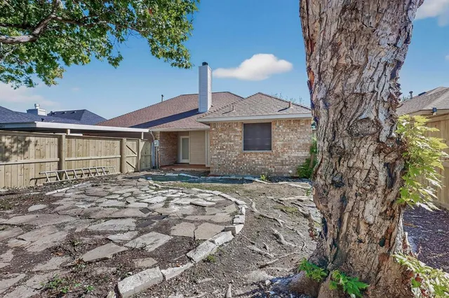 a view of a backyard with large trees and wooden fence