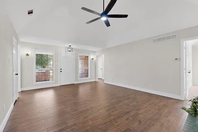 a view of an empty room with window and wooden floor