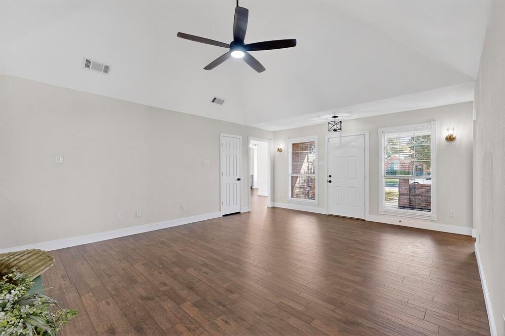 2601 Daisy Lane Rowlett, TX 75089 - Photo 6 of 37 an empty room with wooden floor chandelier fan and windows