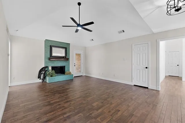 a view of empty room with fireplace and wooden floor