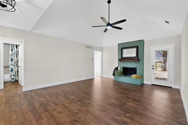 a view of empty room with wooden floor fireplace and window
