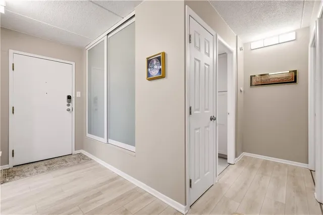 a view of a hallway with wooden floor and closet area