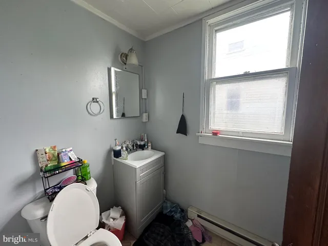 a bathroom with a sink mirror toilet and next to a window