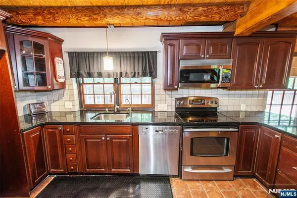a kitchen with granite countertop a stove top oven microwave and cabinets