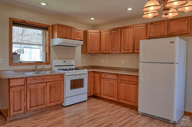 a kitchen with stainless steel appliances granite countertop a refrigerator a sink dishwasher a stove and white countertops with wooden floor