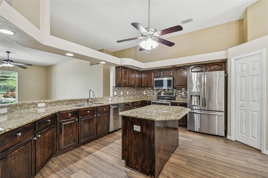 19331 Wind Dancer Street Lutz, FL 33558 - Photo 20 of 92 a kitchen with stainless steel appliances granite countertop hardwood floor sink stove and refrigerator