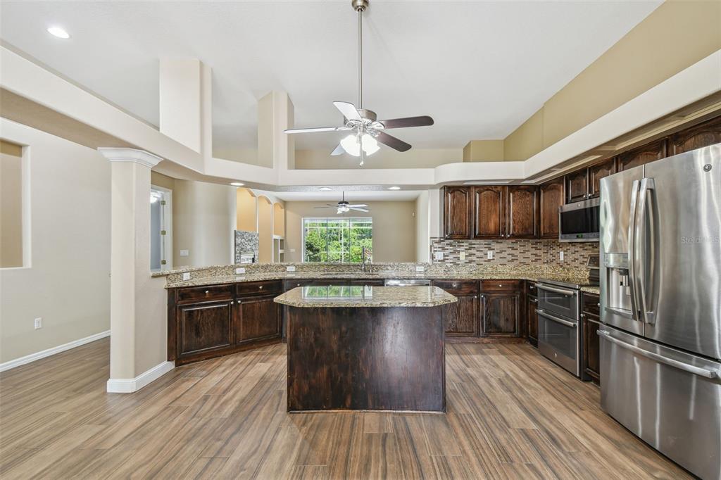19331 Wind Dancer Street Lutz, FL 33558 - Photo 21 of 92 a kitchen with stainless steel appliances granite countertop hardwood floor sink stove dining table and chairs