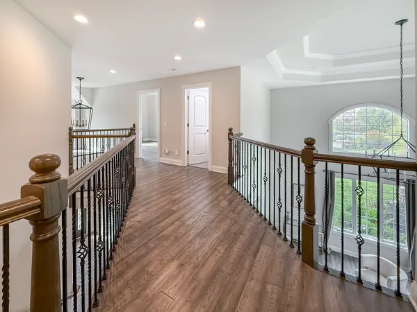 a view of a hallway with wooden floor and windows