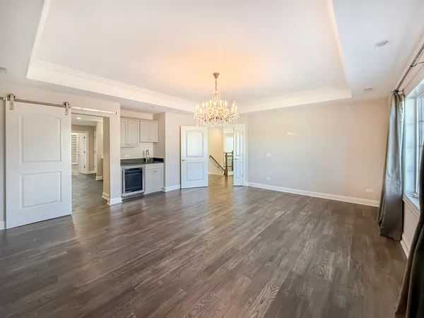 an empty room with wooden floor and kitchen view