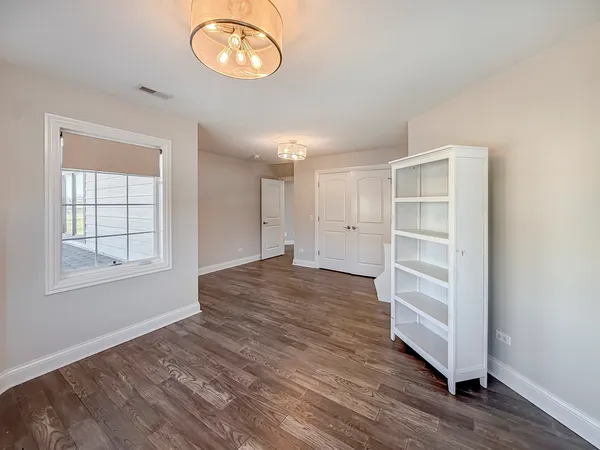 an empty room with wooden floor closet and windows