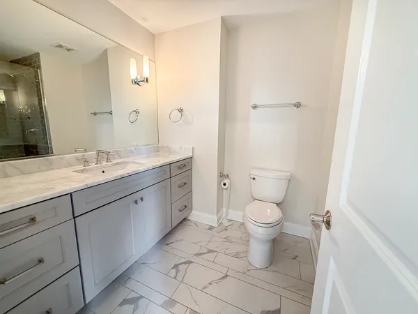 a spacious bathroom with a toilet sink and mirror