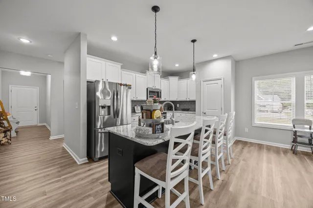 a kitchen with stainless steel appliances a dining table chairs stove and refrigerator