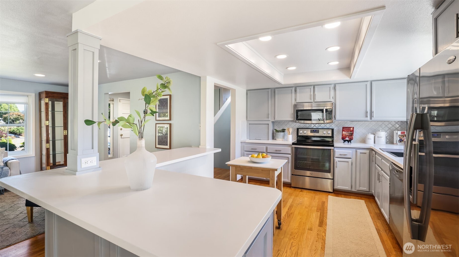 13735 Southeast 172nd Street Renton, WA 98058 - Photo 6 of 29 a kitchen with stainless steel appliances kitchen island granite countertop a refrigerator a stove top oven a sink dishwasher and white cabinets with wooden floor