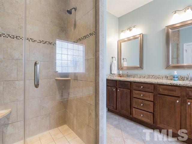 1232 Jogging Court Raleigh, NC 27603 - Photo 14 of 25 a bathroom with a granite countertop sink a mirror and shower