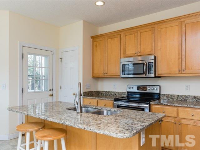 1232 Jogging Court Raleigh, NC 27603 - Photo 6 of 25 a kitchen with kitchen island granite countertop a stove top oven a sink a dining table and chairs