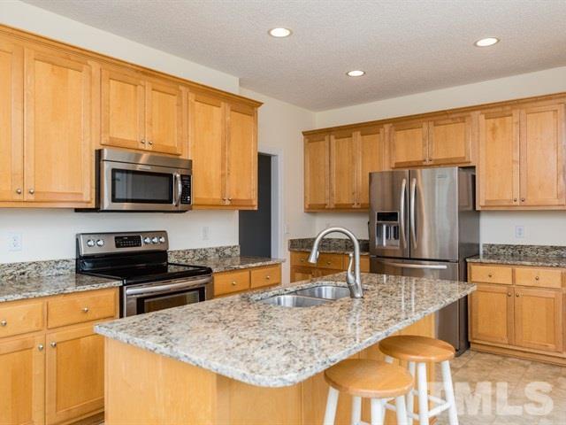 1232 Jogging Court Raleigh, NC 27603 - Photo 7 of 25 a kitchen with granite countertop a sink a stove top oven a refrigerator cabinets and a counter top space