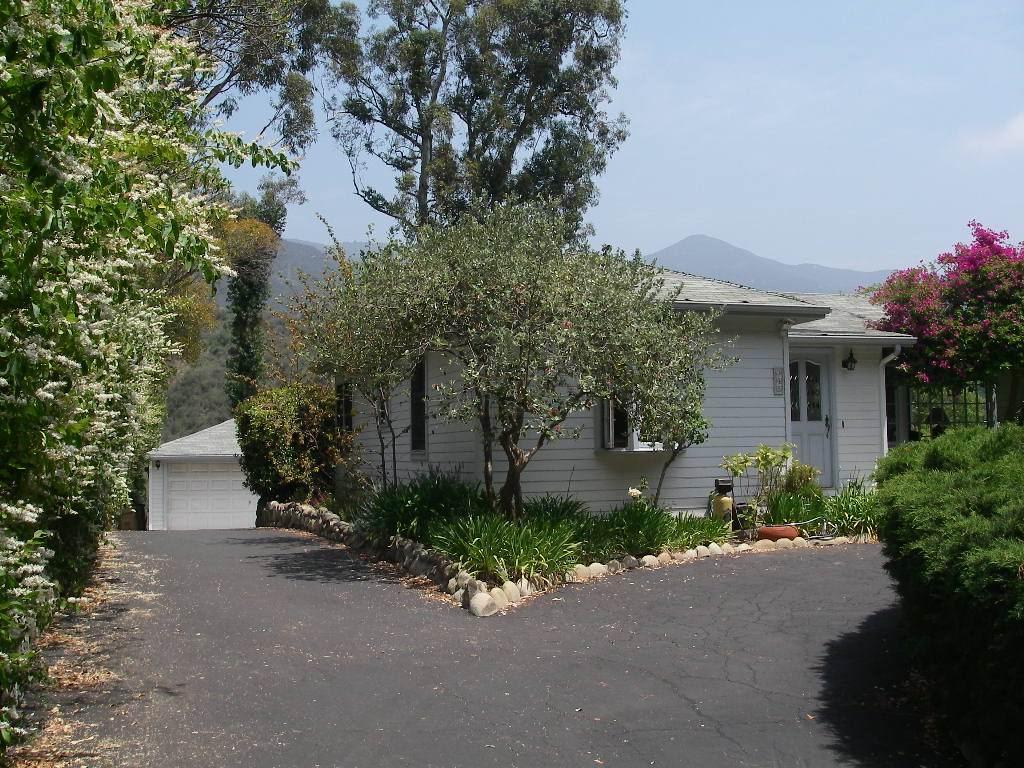 a front view of a house with plants and trees