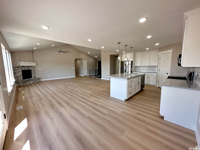 1171 West 2330 North Helper, UT 84526 - Photo 26 of 26 Kitchen with open floor plan, light stone countertops, decorative light fixtures, white cabinets, and a center island with sink