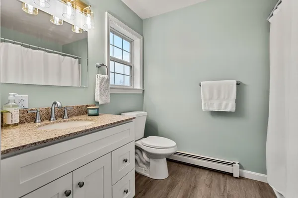 a bathroom with a granite countertop toilet sink and mirror