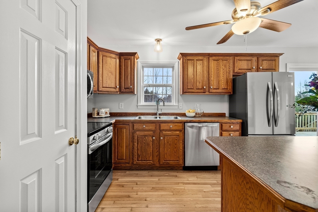 454 Little Pond Road Sandwich, NH 03227 - Photo 10 of 38 a kitchen with stainless steel appliances granite countertop a refrigerator a sink dishwasher a stove and white countertops with wooden floor