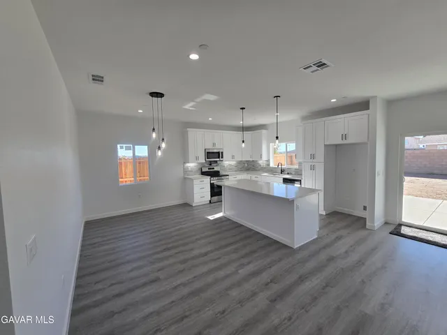 a large kitchen with stainless steel appliances granite countertop a large counter top and a wooden floors