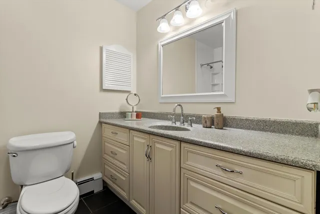 a bathroom with a granite countertop toilet sink and mirror