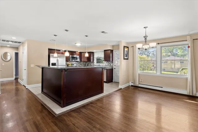 a kitchen with stainless steel appliances granite countertop a stove top oven a refrigerator a sink with wooden floors and cabinets