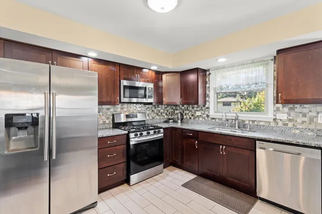 a kitchen with stainless steel appliances granite countertop a refrigerator a sink a stove top oven and a refrigerator