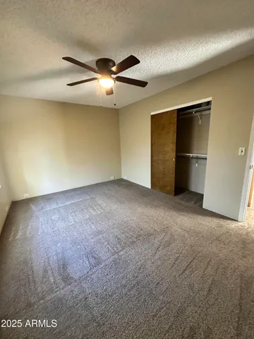 a view of an empty room with chandelier fan and window