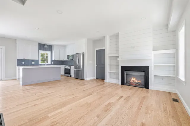 a view of empty room with a fireplace and kitchen view