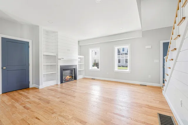 a view of empty room with wooden floor and fireplace