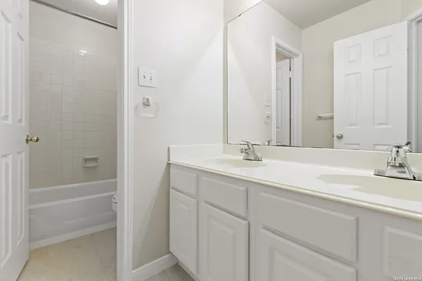 a bathroom with a double vanity sink a mirror and a bathtub