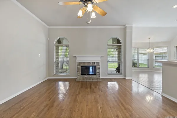 a view of an empty room with wooden floor fireplace and a window
