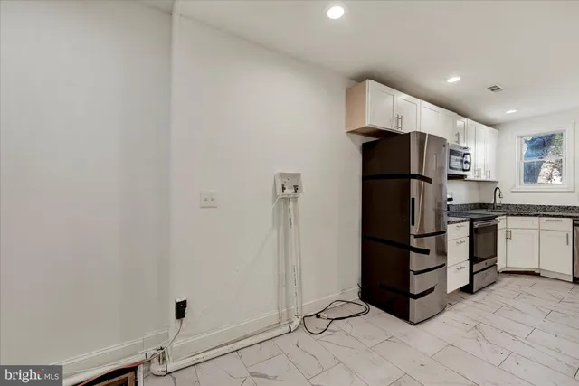 a kitchen with white cabinets and refrigerator