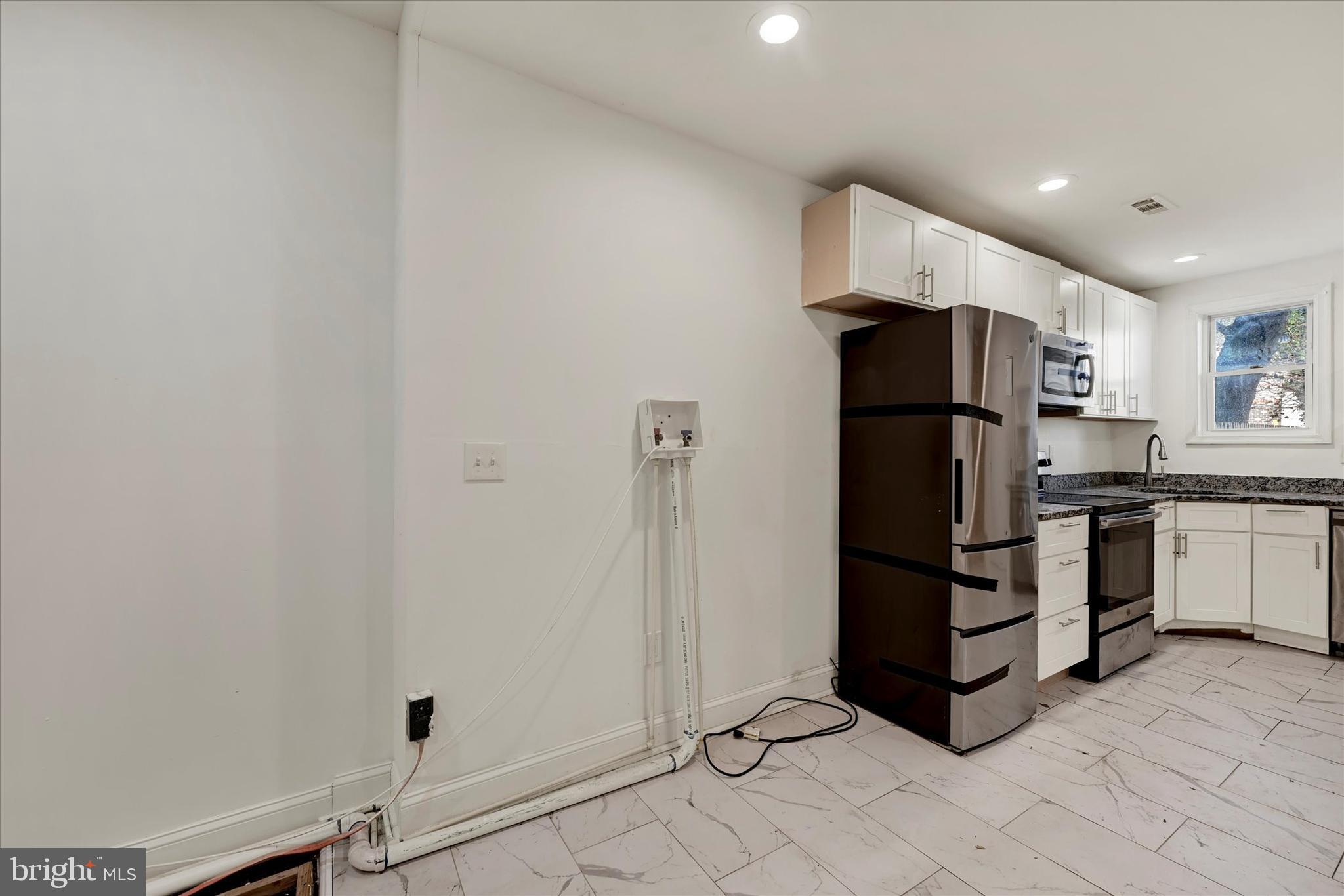 346 East 25th Street Baltimore, MD 21218 - Photo 15 of 31 a kitchen with white cabinets and refrigerator