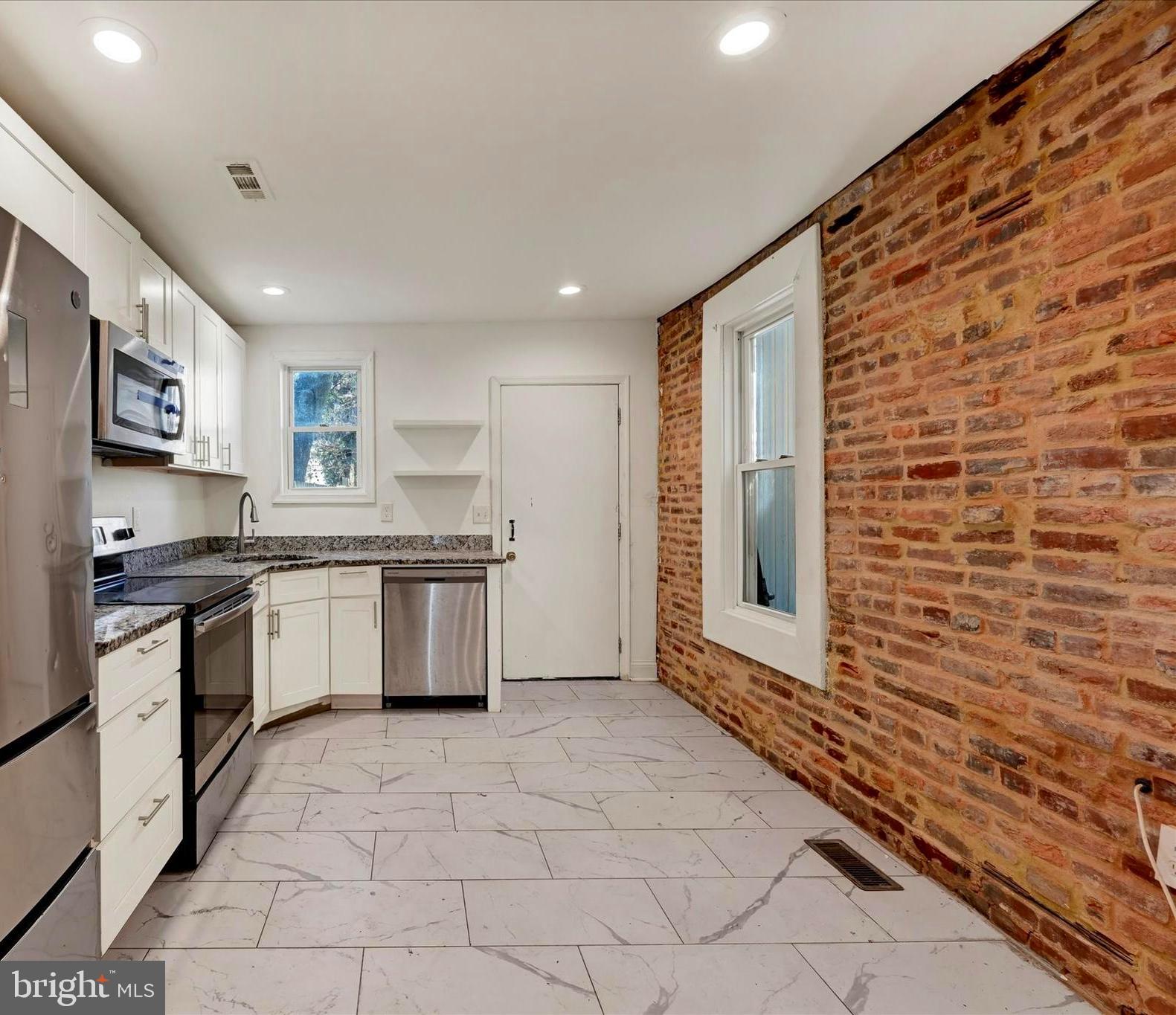 346 East 25th Street Baltimore, MD 21218 - Photo 16 of 31 a kitchen with stainless steel appliances granite countertop a stove a sink and a refrigerator
