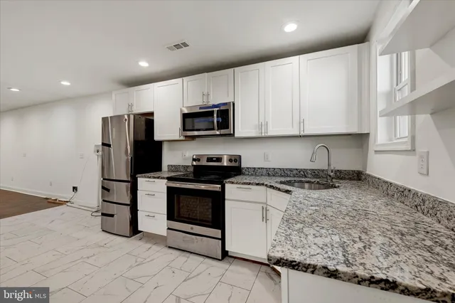 a kitchen with stainless steel appliances granite countertop a stove a refrigerator and a sink