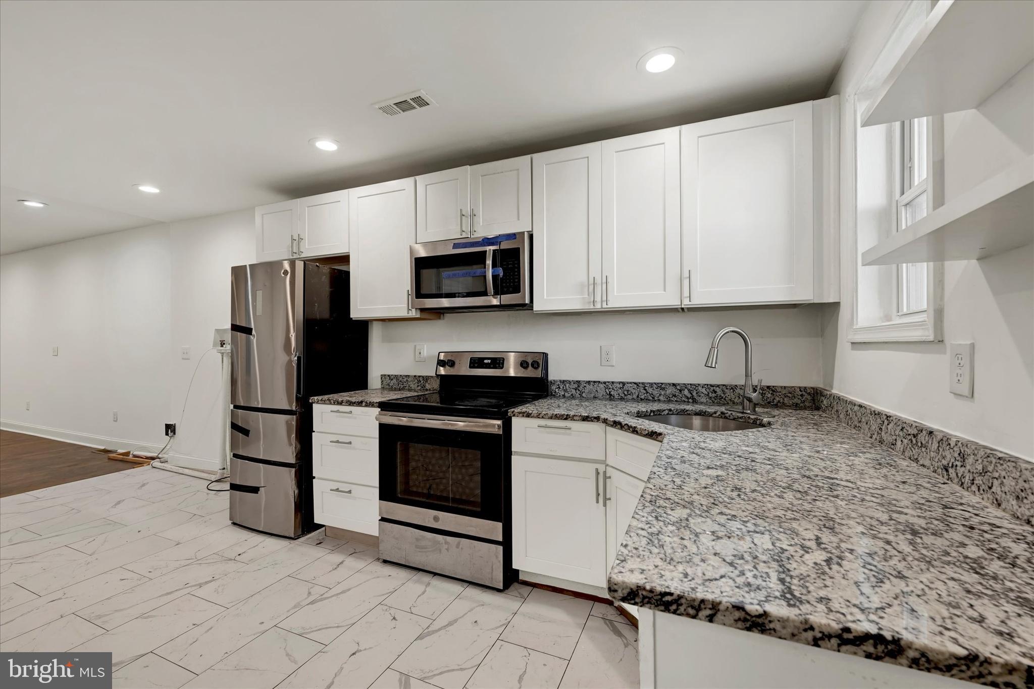 346 East 25th Street Baltimore, MD 21218 - Photo 18 of 31 a kitchen with stainless steel appliances granite countertop a stove a refrigerator and a sink
