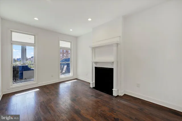 an empty room with wooden floor and fireplace