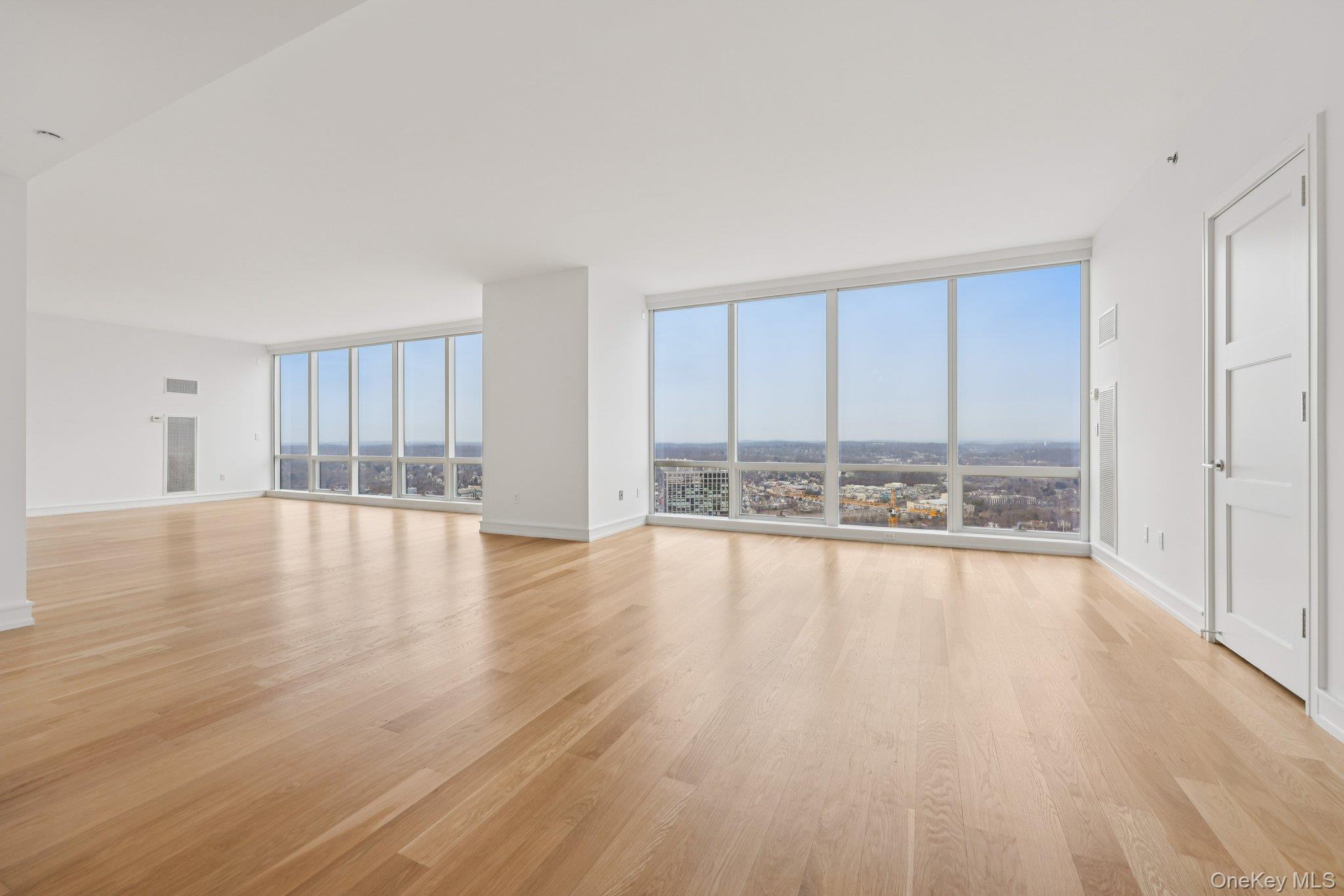 1 Renaissance Square, Unit PH40C White Plains, NY 10601 - Photo 2 of 23 a view of empty room with wooden floor and floor to ceiling window