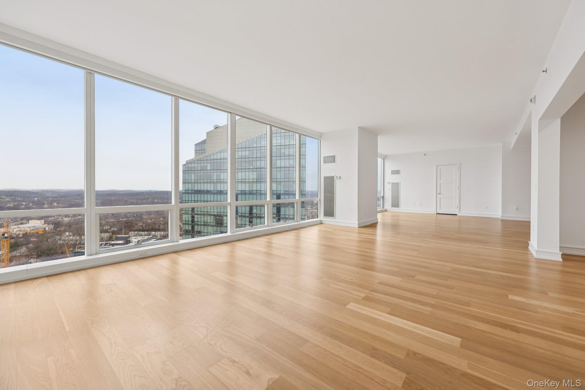 1 Renaissance Square, Unit PH40C White Plains, NY 10601 - Photo 7 of 25 Unfurnished living room with light wood-style flooring, expansive windows, and a city view