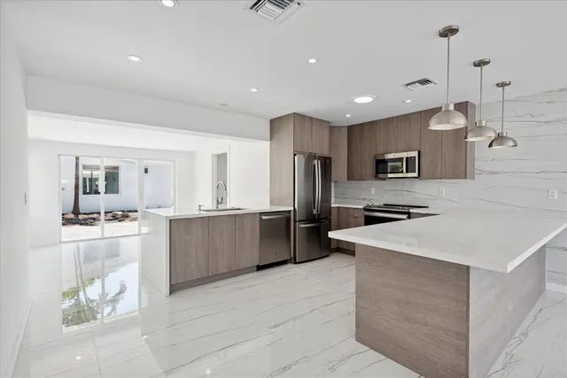 a large kitchen with stainless steel appliances kitchen island granite countertop a refrigerator a sink a stove and a cabinets