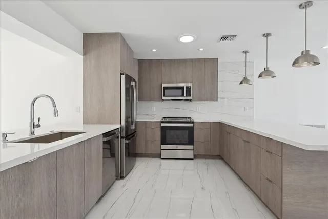 a kitchen with stainless steel appliances kitchen island a sink stove and refrigerator
