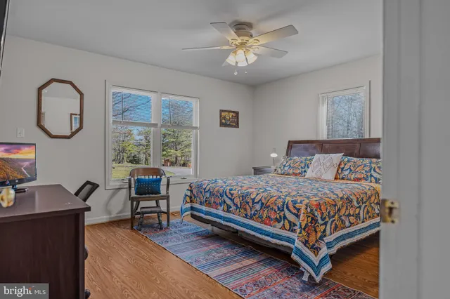a bedroom with a bed a desk and chair with a large window