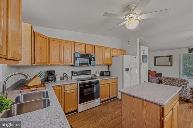 a kitchen with stainless steel appliances granite countertop a stove a sink dishwasher and a refrigerator with wooden floor