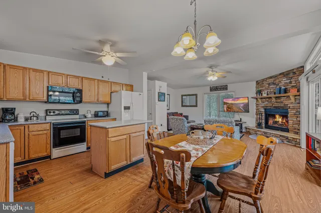 a dining room with stainless steel appliances kitchen island granite countertop a table chairs and a refrigerator