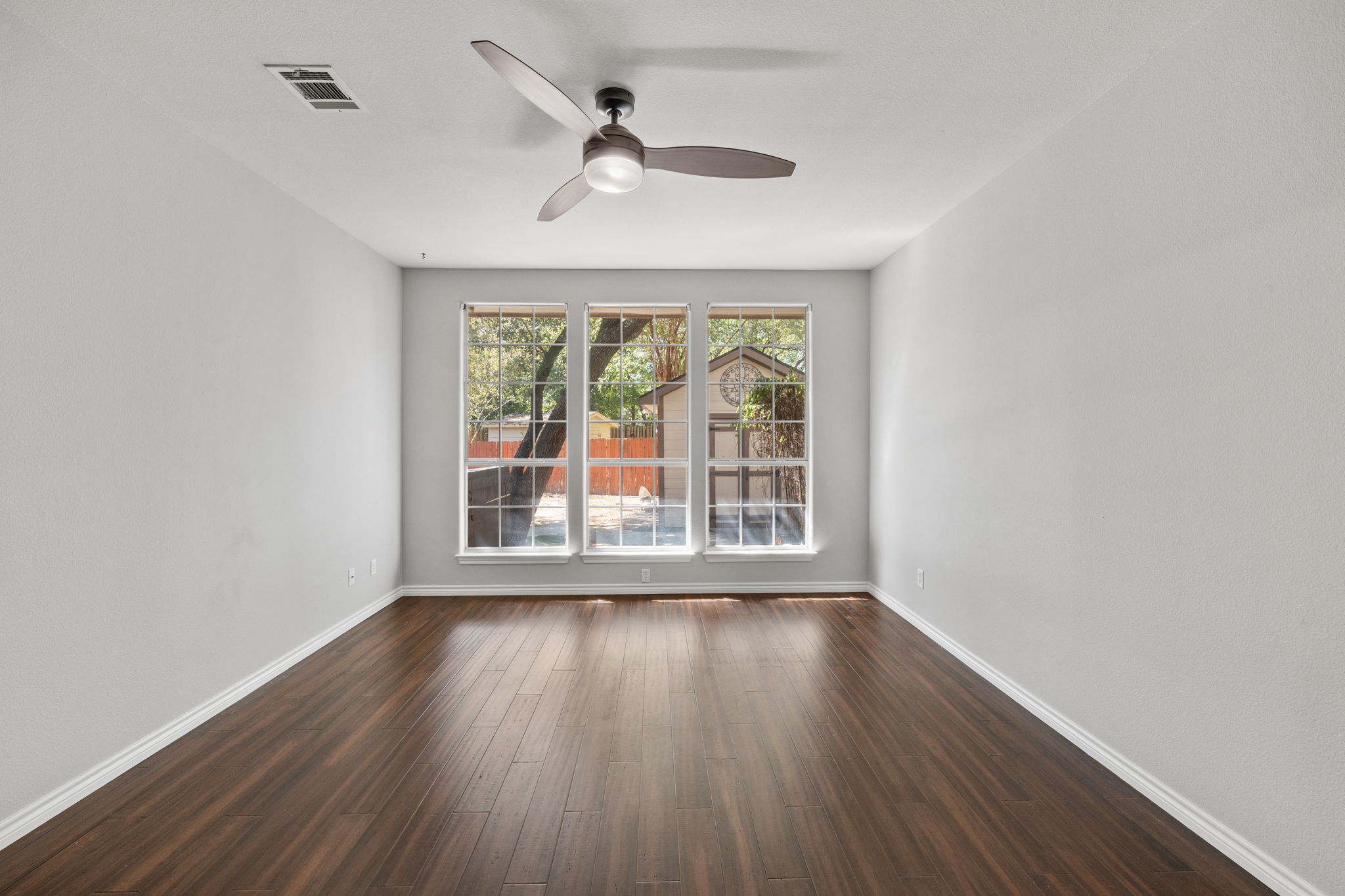 2211 Spring Hollow Path Round Rock, TX 78681 - Photo 21 of 36 Rich wood-look flooring and three large windows highlight this versatile, open living area.