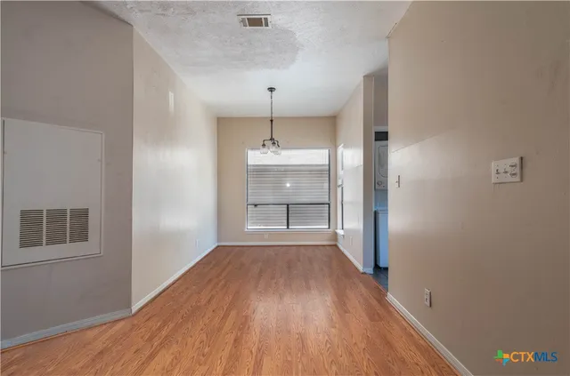 a view of a hallway with wooden floor and a kitchen